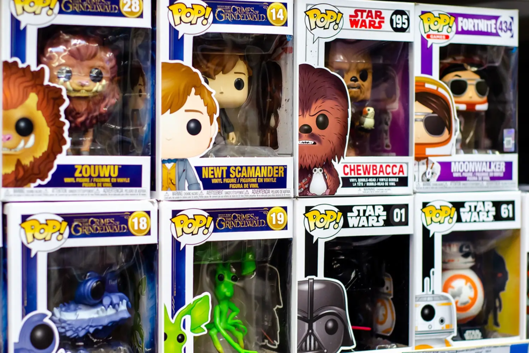 A display of Funko Pop! collectible figures in their boxes, including characters from "Fantastic Beasts," "Star Wars," and "Fortnite," neatly arranged on shelves using Toy Grading Terminology Australia standards.