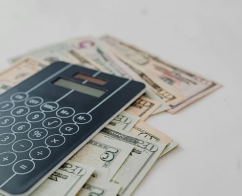A close-up of a calculator and US dollar banknotes, symbolizing financial calculation and budgeting.