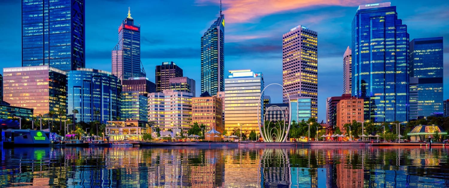 Property Valuations Perth Property Valuations Perth, A vibrant city skyline at sunset, with tall modern buildings reflected in calm water. As city lights begin to illuminate the scene, the beauty showcases why Property Valuations Perth are essential for this dynamic urban landscape.