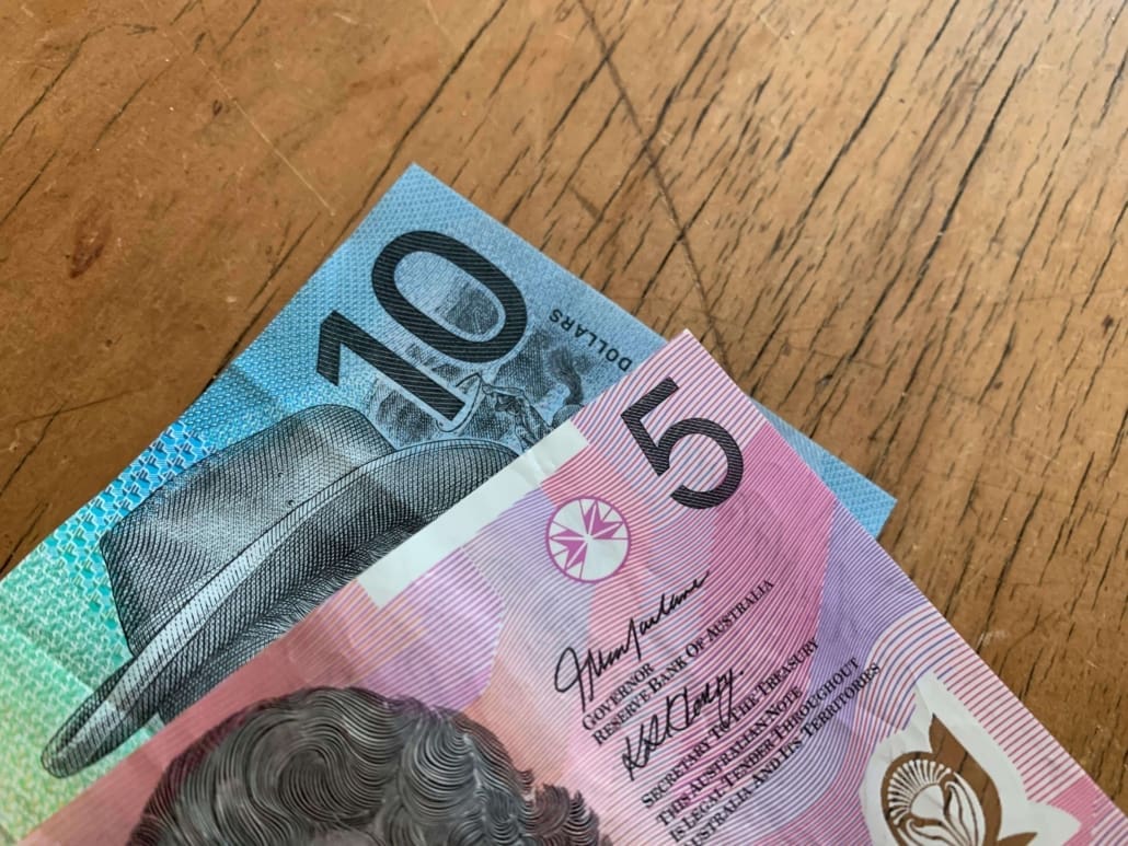 Two Australian banknotes, a blue $10 and a pink $5, partially overlap on a wooden surface. Both notes display portraits and security features, ideal props for illustrating SMSF Asset CGT Valuations in financial presentations.